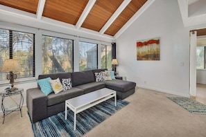A living room with a sectional sofa, a coffee table, and a painting on the wall.