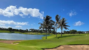 Ein Golfplatz mit See, Palmen und blauem Himmel.
