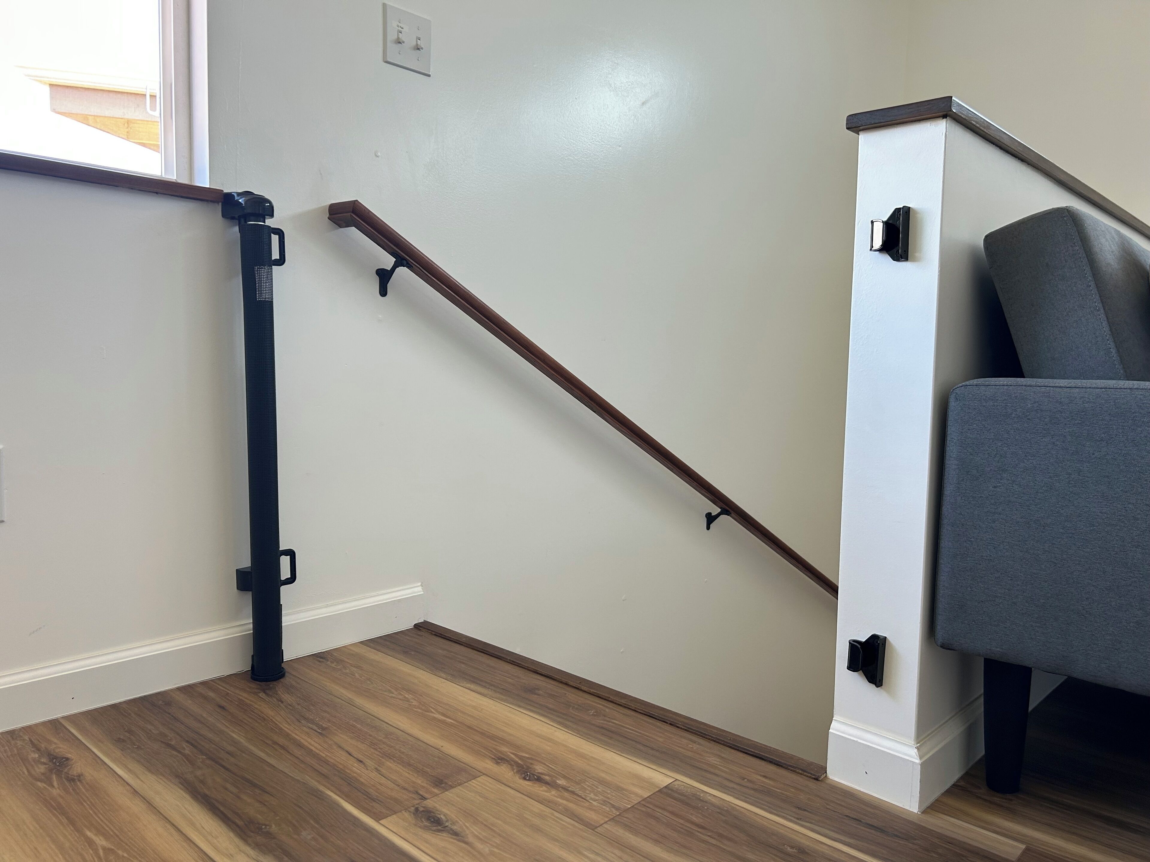 A staircase with a wooden handrail and a grey chair at the top.