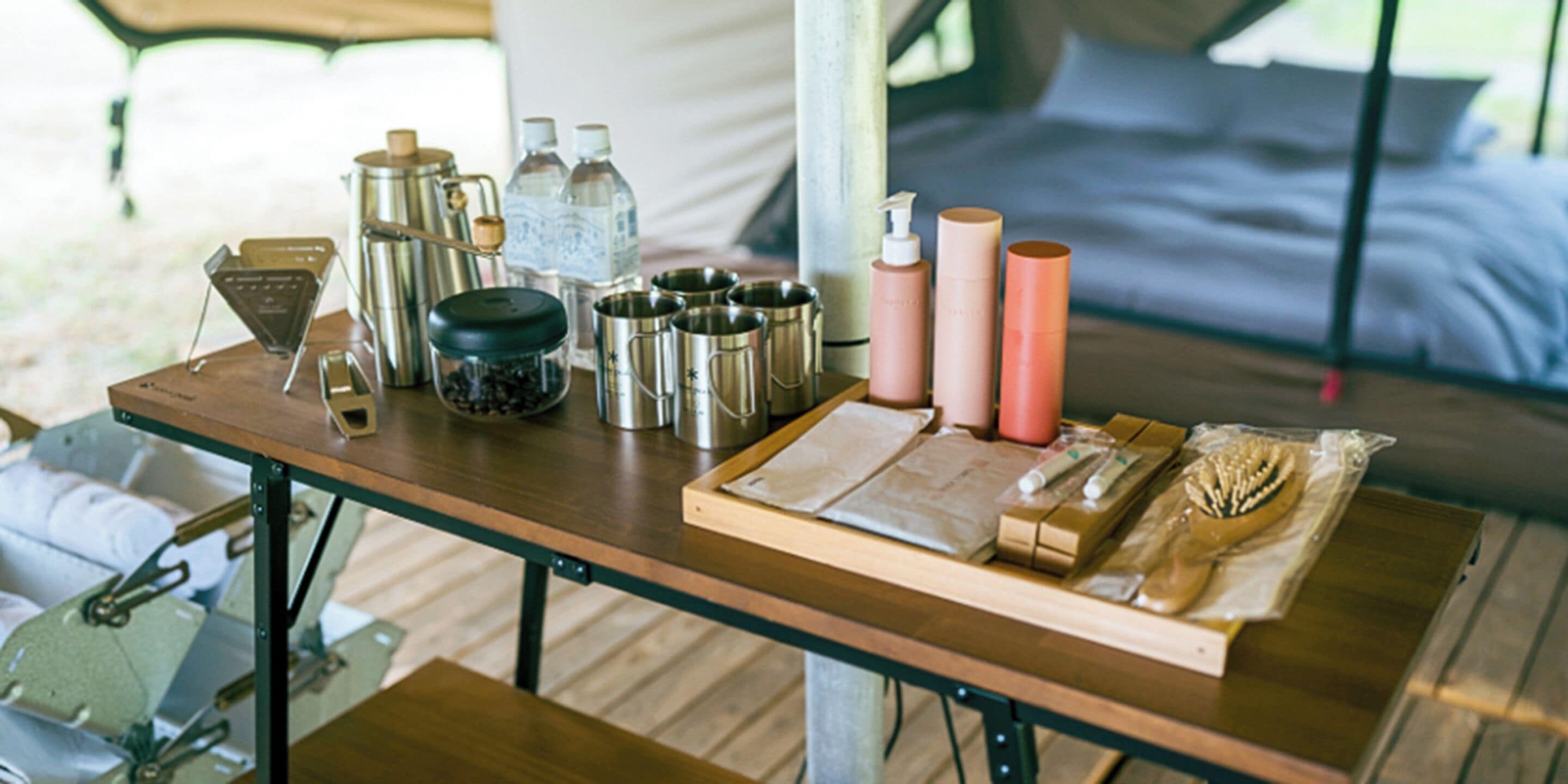 A wooden table with kitchen utensils, bottles, and a cutting board.