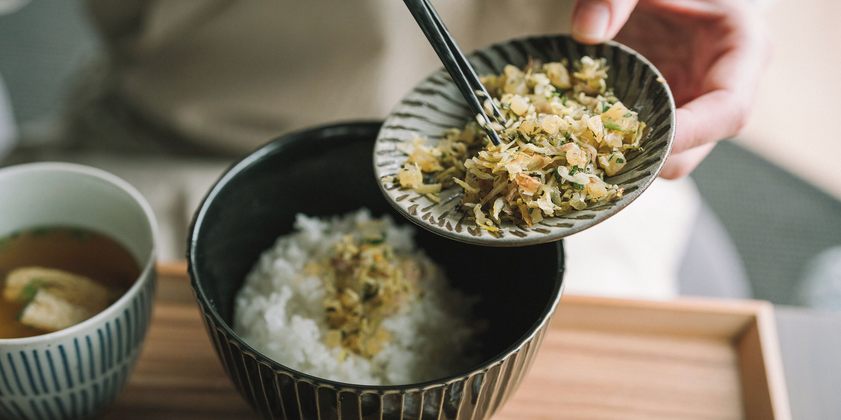 A bowl of white rice with a topping being served into a larger bowl.