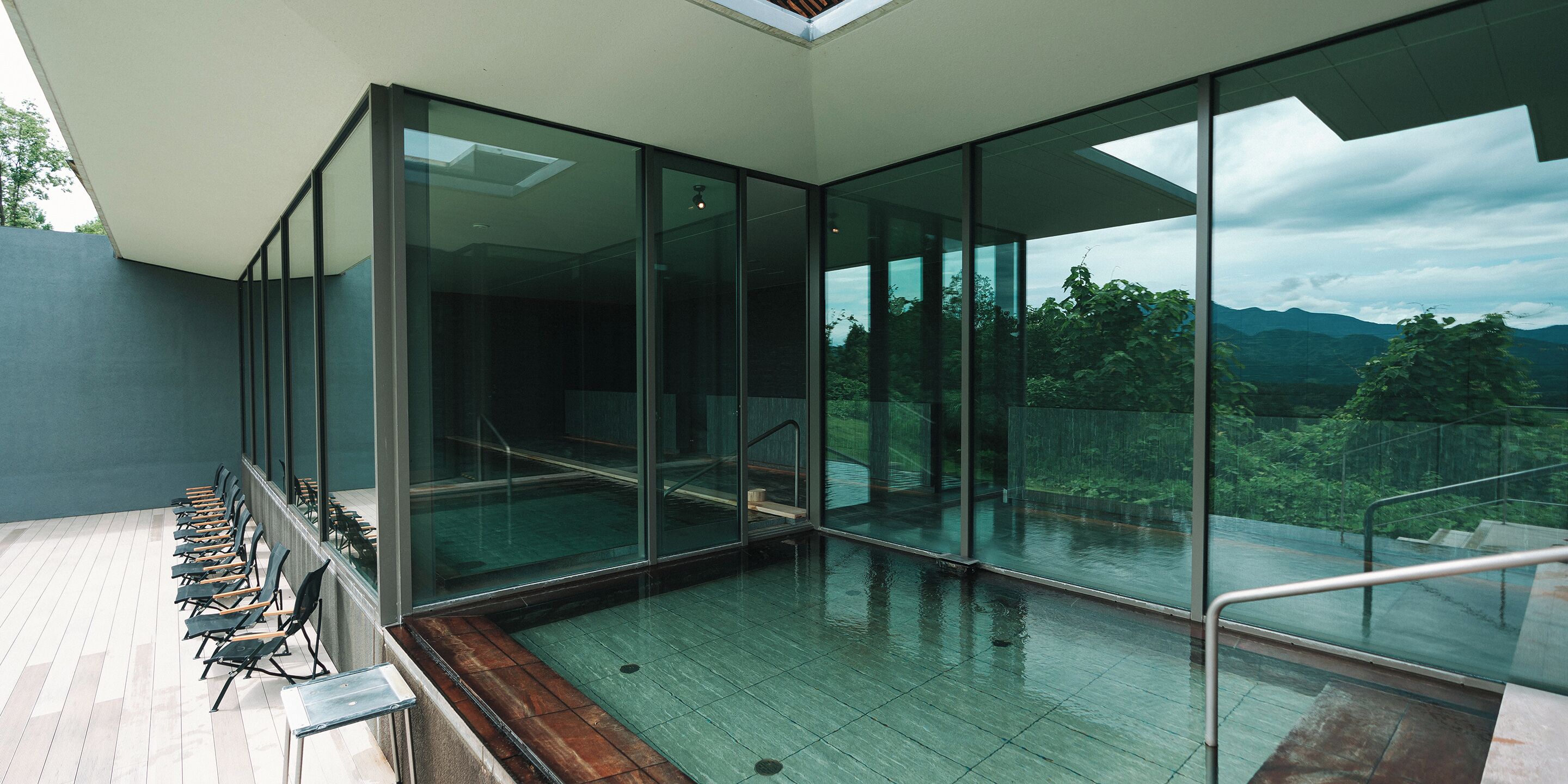 A modern interior with a glass wall offering a view of a mountainous landscape.