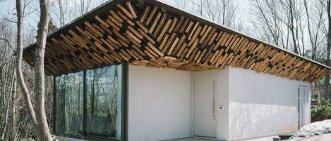 A modern building with a sloped roof made of wooden beams, large glass windows, and a door.