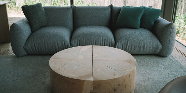 A grey sofa with a round wooden coffee table in front. - Snow Peak FIELD SUITE SPA HEADQUARTERS (Sanjo)