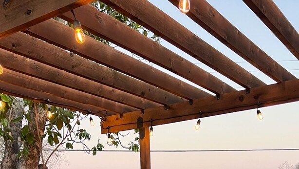 An outdoor patio with a round table and four chairs, a fire pit, and string lights. - Home away from Home- The Willow Serenity Home (San Antonio)