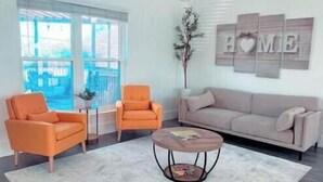 A modern living room with a sofa, two armchairs, a coffee table, and a decorative wall piece. - Home away from Home- The Willow Serenity Home (San Antonio)
