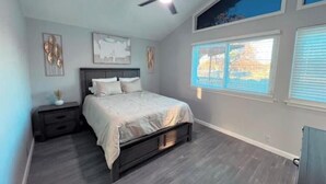 A bedroom with a bed, nightstands, a ceiling fan, and a window with blinds. - Home away from Home- The Willow Serenity Home (San Antonio)
