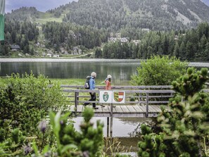 Une jetée en bois s’étendant au-dessus d’un lac, sur laquelle se promènent deux personnes.