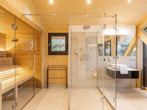 A modern bathroom with a glass shower enclosure, wooden walls, a bench, and a sink with a mirror.