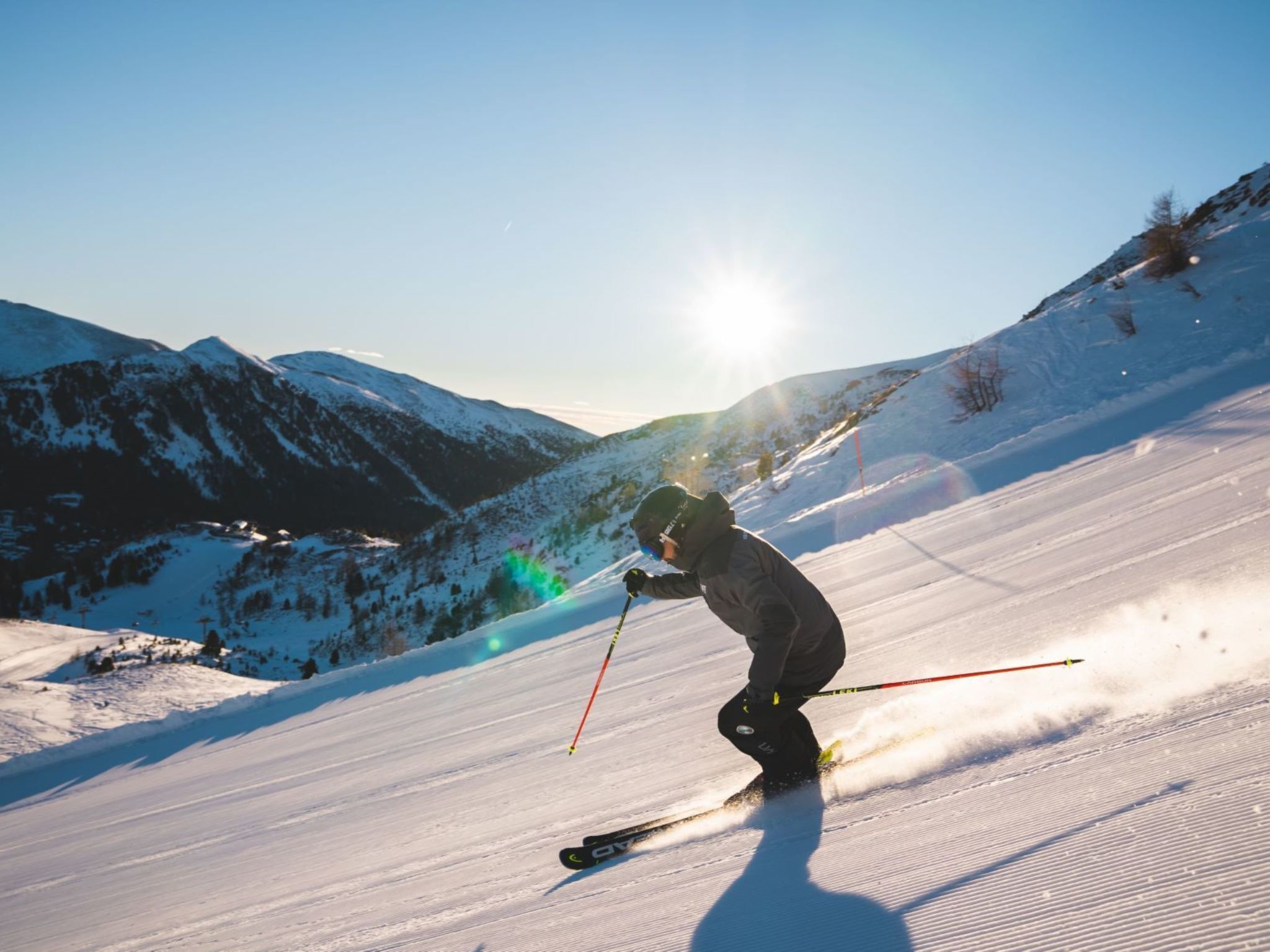 Un skieur sur une pente enneigée, avec des montagnes en arrière-plan.