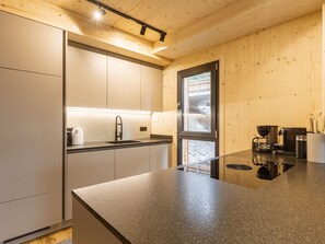Una cocina moderna con encimera de granito, electrodomésticos de acero inoxidable y paneles de madera.