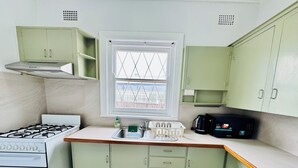 Une cuisine compacte équipée d’une cuisinière à gaz, d’un four à micro-ondes et de meubles de couleur verte.