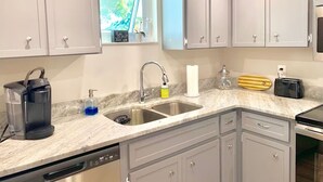 A modern kitchen with grey cabinets, a double sink, a coffee maker, and a toaster. - Punta Breeze 2-bedroom townhome, pool, boat dock & WiFi in relaxing Punta Gorda (Punta Gorda)