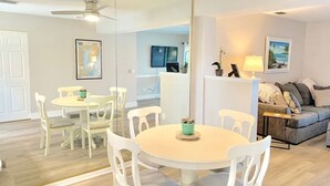 A modern living room with a round dining table, white chairs, a grey sofa, and a ceiling fan. - Punta Breeze 2-bedroom townhome, pool, boat dock & WiFi in relaxing Punta Gorda (Punta Gorda)