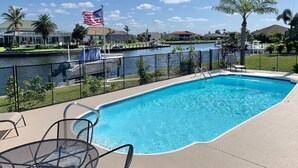 A swimming pool with a view of a body of water and a flag. - Punta Breeze 2-bedroom townhome, pool, boat dock & WiFi in relaxing Punta Gorda (Punta Gorda)