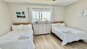 A bedroom with two single beds, a wooden dresser, a window with curtains, a framed picture on the wall, and a wooden floor. - Punta Breeze 2-bedroom townhome, pool, boat dock & WiFi in relaxing Punta Gorda (Punta Gorda)