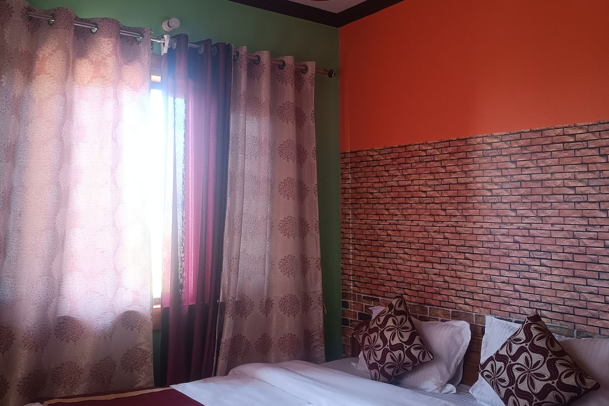 A room with a bed, curtains, a brick-patterned wall, and a ceiling fan.