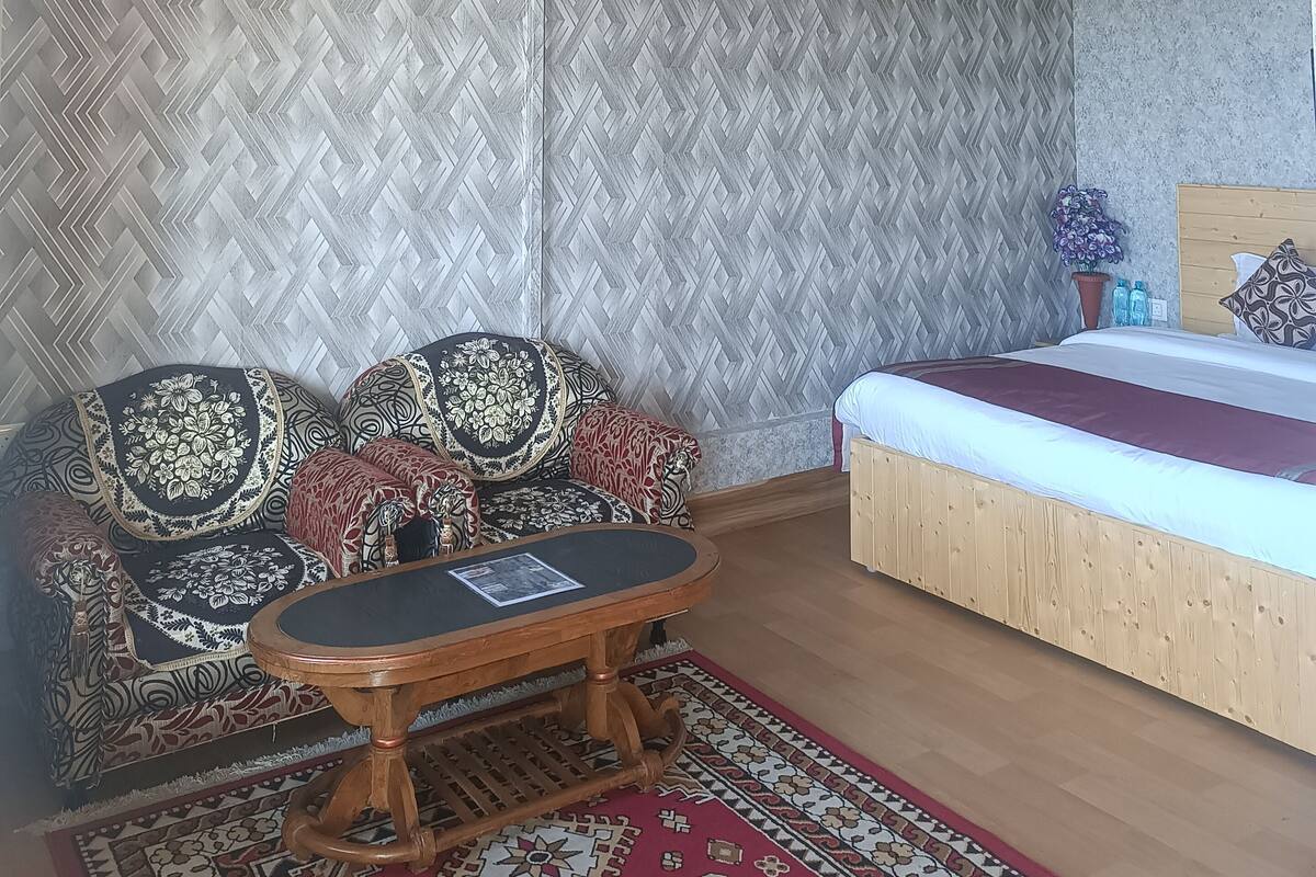 A room with a bed, a sofa set, a coffee table, and a ceiling fan.