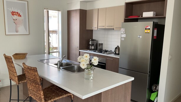 A modern kitchen with a central island, stainless steel appliances, and wicker bar stools. - Searenity only 750 m to the beach, pet friendly (St Leonards)