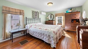 A bedroom with a bed, dresser, and a desk with a lamp.