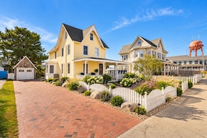 A residential street with two houses, a garage, and a water tower.