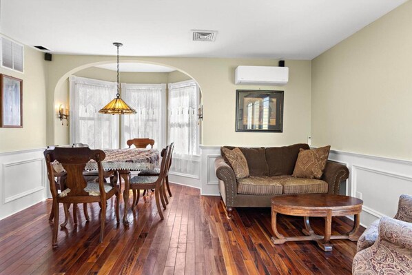 A living room with a wooden dining table, chairs, a sofa, and a coffee table. - Poolside Home Block From Beach (Beach Haven)