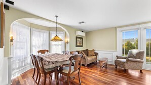 A spacious room with a wooden dining table, a sofa, and a patterned armchair.