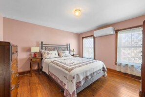 A bedroom with a bed, a nightstand, a dresser, and an air conditioning unit. - Poolside Home Block From Beach (Beach Haven)