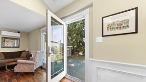 Sala de estar con puerta de vidrio corrediza que da a una terraza, un sofá y un sillón estampado.