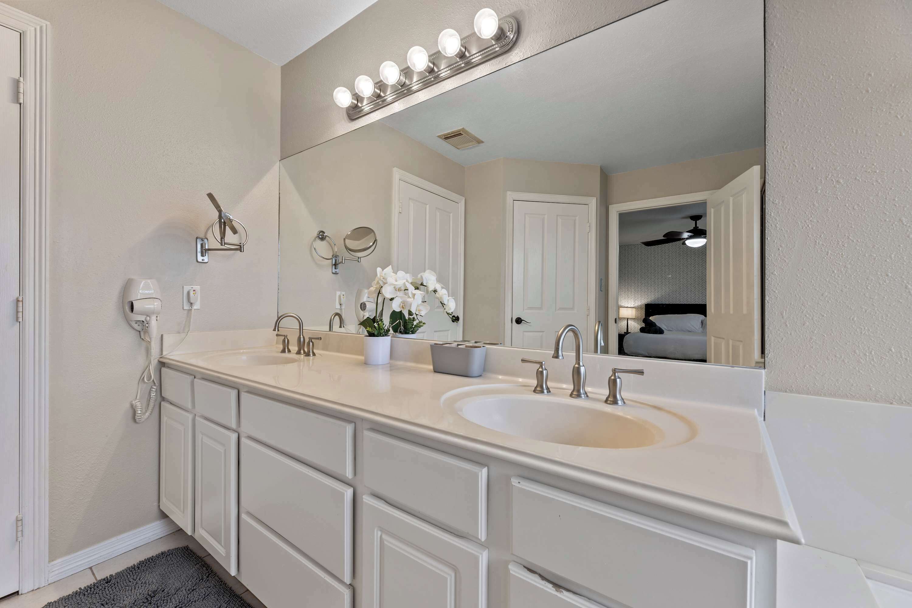 A bathroom with a double sink, vanity, mirror, and a light fixture above the mirror.