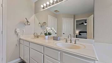 A bathroom with a double sink, vanity, mirror, and a light fixture above the mirror.