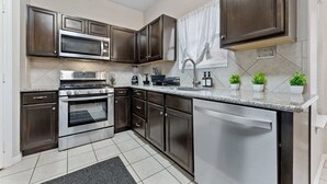 A modern kitchen with dark wood cabinets, stainless steel appliances, and a granite countertop. - Luxurious Home with Great Pool Area (Willis)