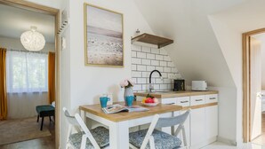 Une cuisine moderne avec un îlot central blanc, un luminaire suspendu et une vue sur l’extérieur.