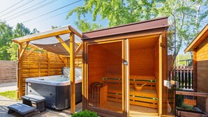 Un sauna en bois avec une porte en verre, un jacuzzi et une terrasse en bois.