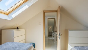Une chambre avec une lucarne, un plancher en bois et une vue sur la salle de bain.