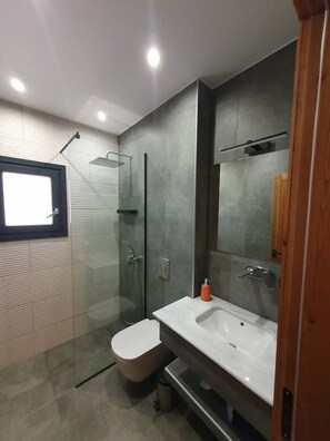 A modern bathroom with a glass-enclosed shower, a white sink, and a large mirror. - Casa Bonita 2 Bedroom apt with the Best view in Town! (Palairos)