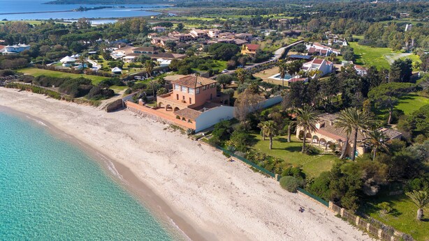 An aerial view of a coastal area with a beach, a large building with a red roof, and surrounding greenery. - Villa Olga in exclusive setting with private access to Nora beach (Pula)