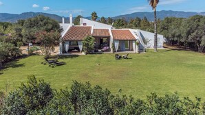 A modern house with a white exterior and terracotta roof tiles, surrounded by a well-maintained lawn and trees. - Villa Olga in exclusive setting with private access to Nora beach (Pula)