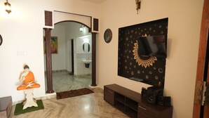 Un soggiorno moderno con pavimento in marmo, una statua di Buddha, un televisore montato su una parete decorata e un mobile TV in legno scuro.
