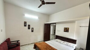 Camera da letto con un letto, una panca, una ventola a soffitto e una porta che dà su un'altra stanza.