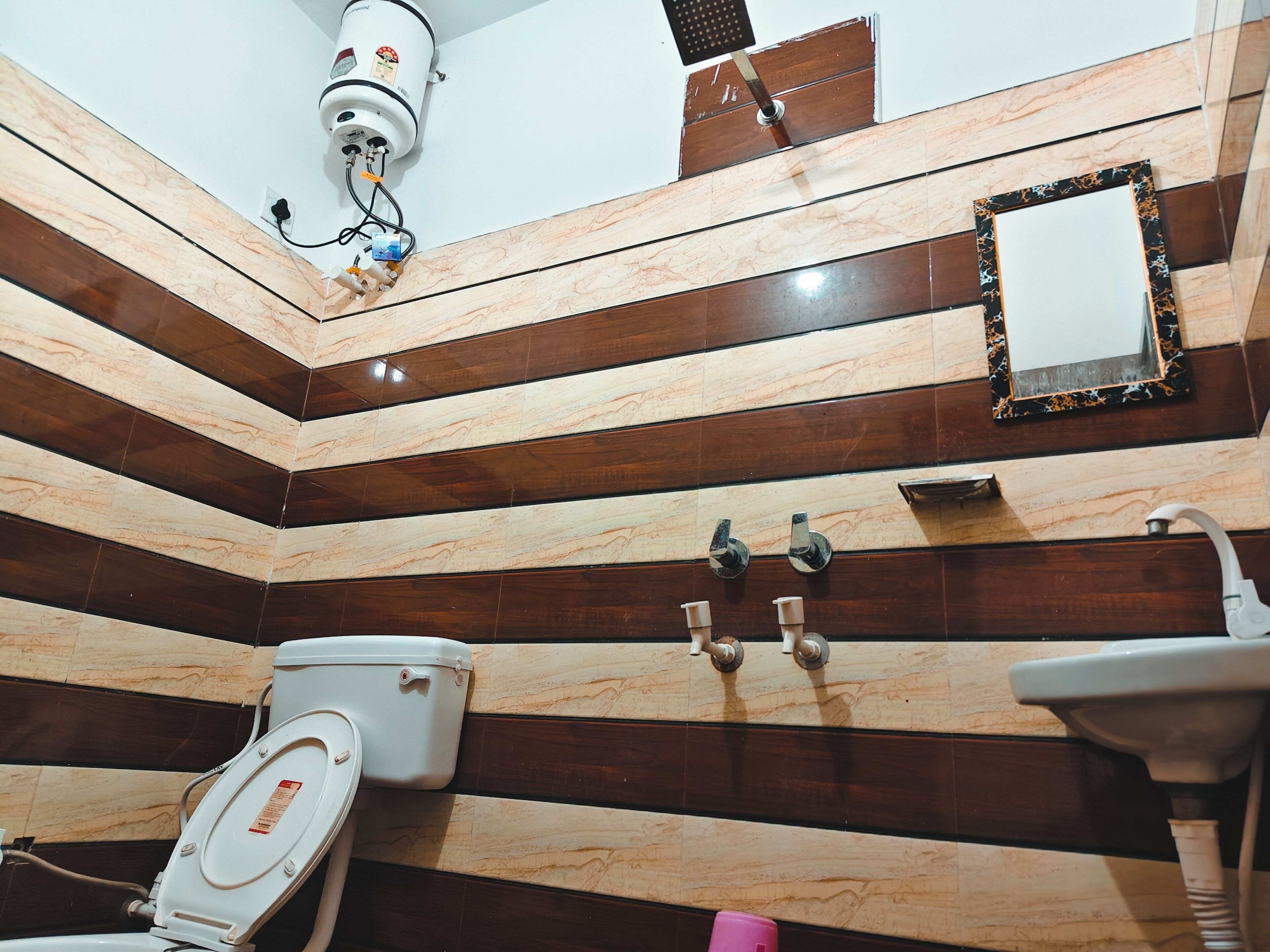 A bathroom with striped tile walls, a toilet, a sink, and a mirror.