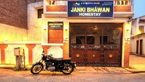 Ένα κτίριο με μια πινακίδα που γράφει «Janki Bhawan Home Stay» και μια μοτοσικλέτα σταθμευμένη μπροστά.