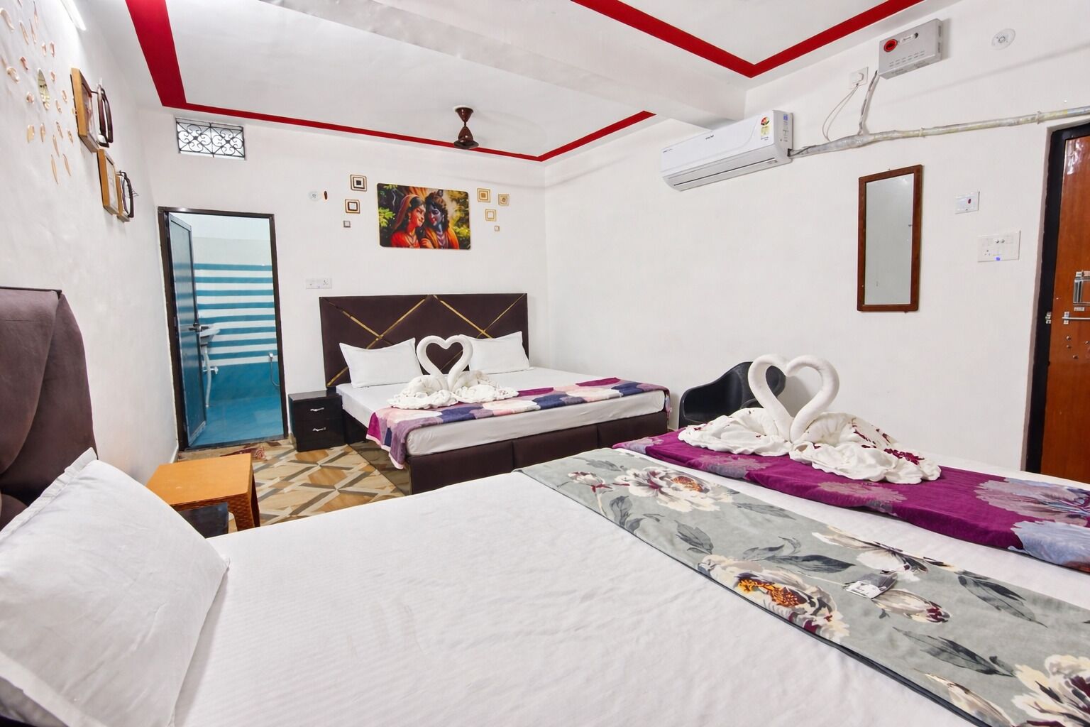 Une chambre d’hôtel avec deux lits, un ventilateur de plafond, un appareil de climatisation et un miroir.