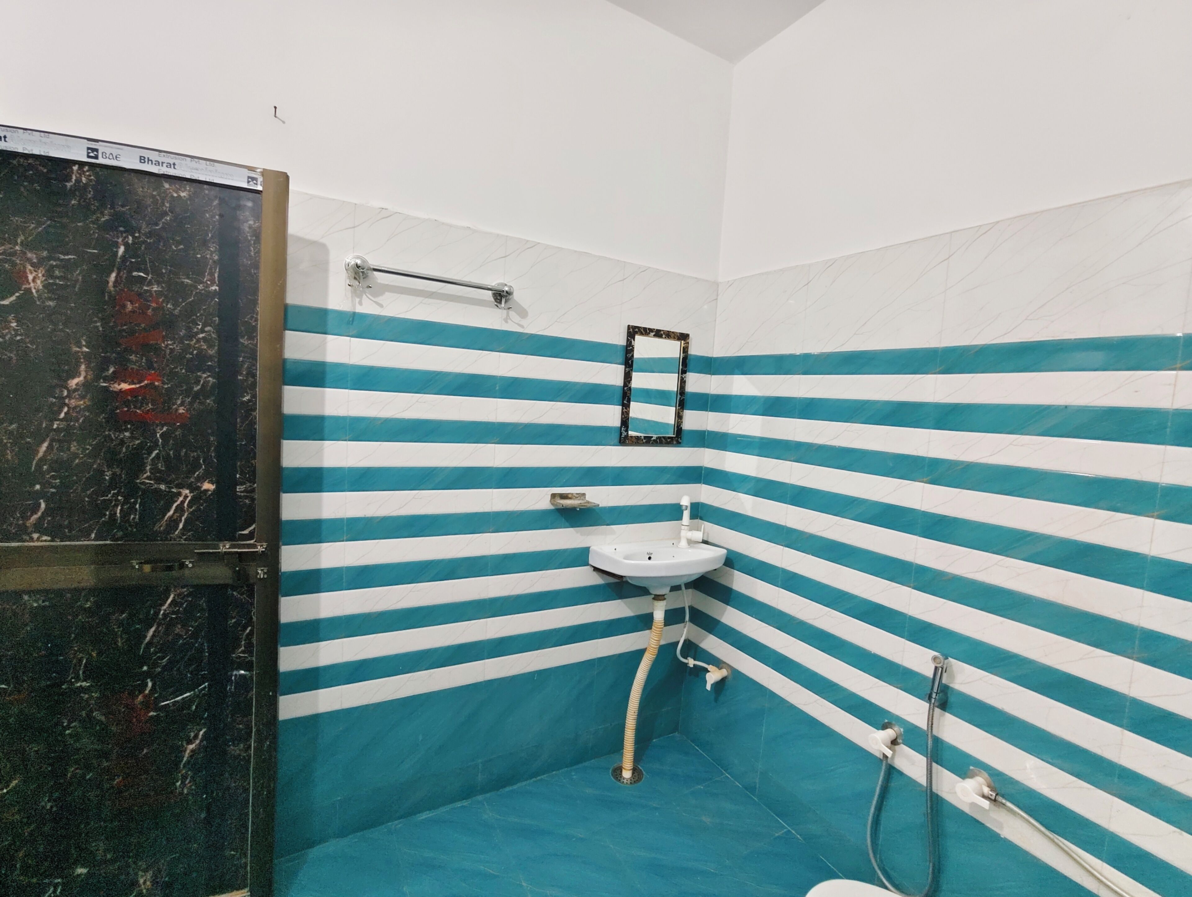 Une salle de bain avec des murs à rayures, un lavabo, un miroir et une douche.