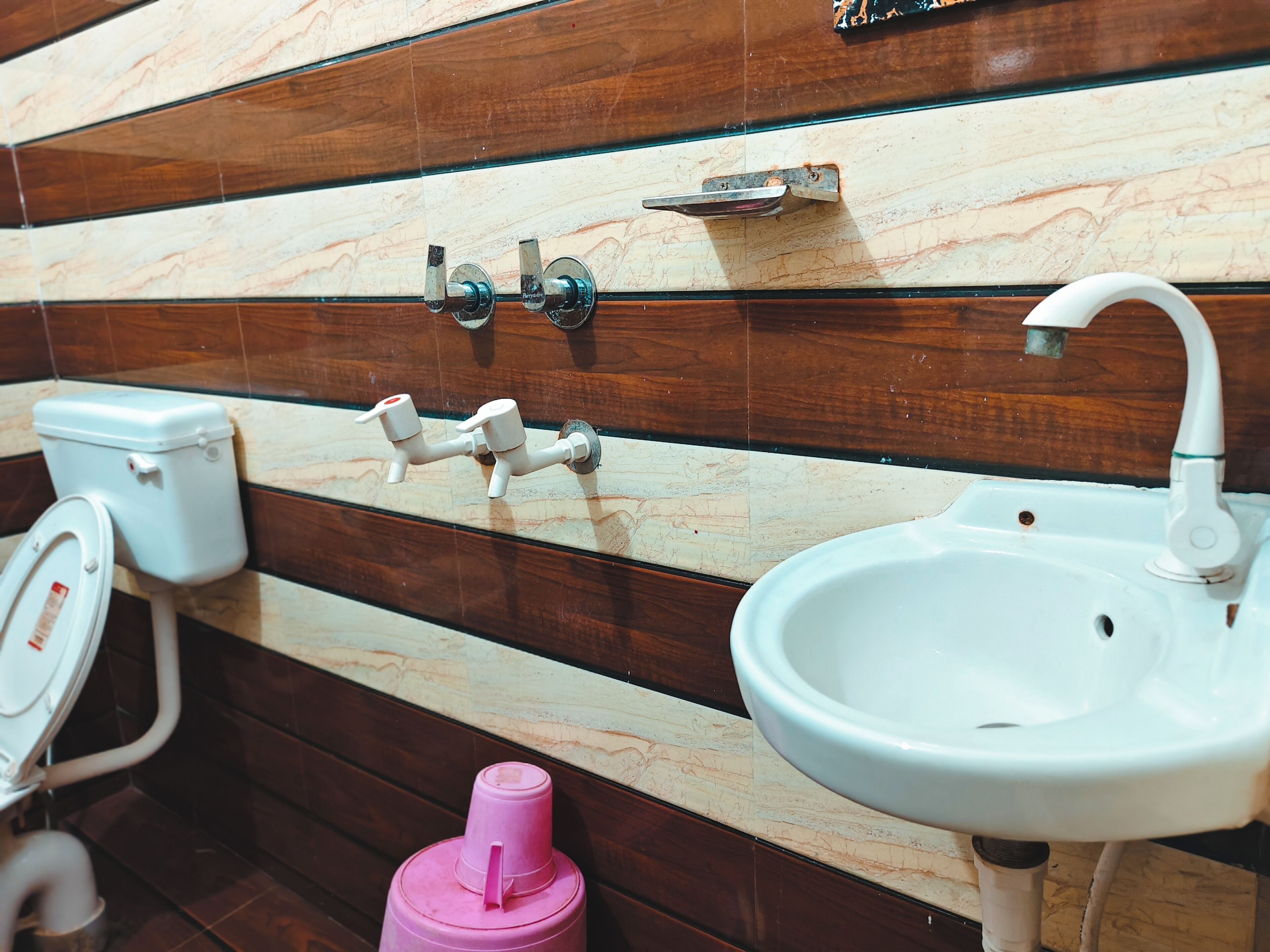 A bathroom with a toilet, sink, and a pink water dispenser.