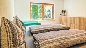 Een slaapkamer met een bed, een raam, een nachtkastje en een plant.