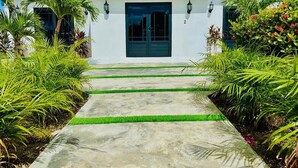 A white building with a dark roof, a central door, and two wall-mounted lights. - Eagle Stays Aruba (Oranjestad)