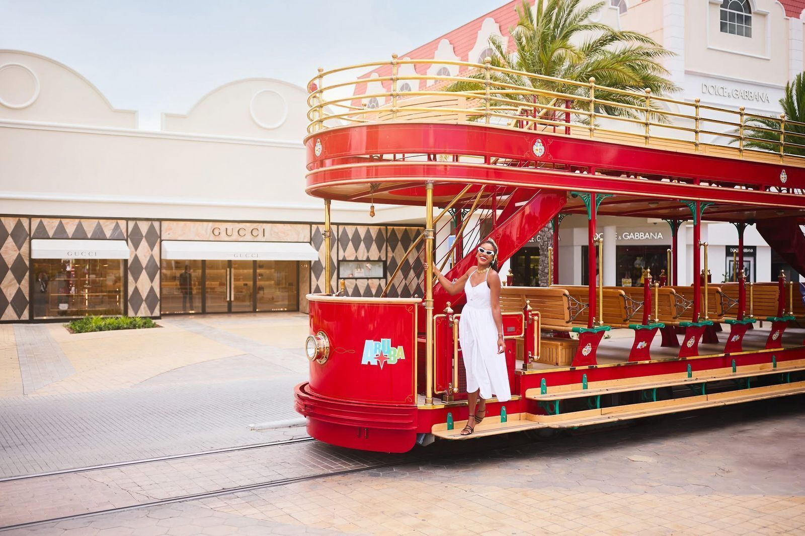 A red double-decker tram with a woman standing on the front.