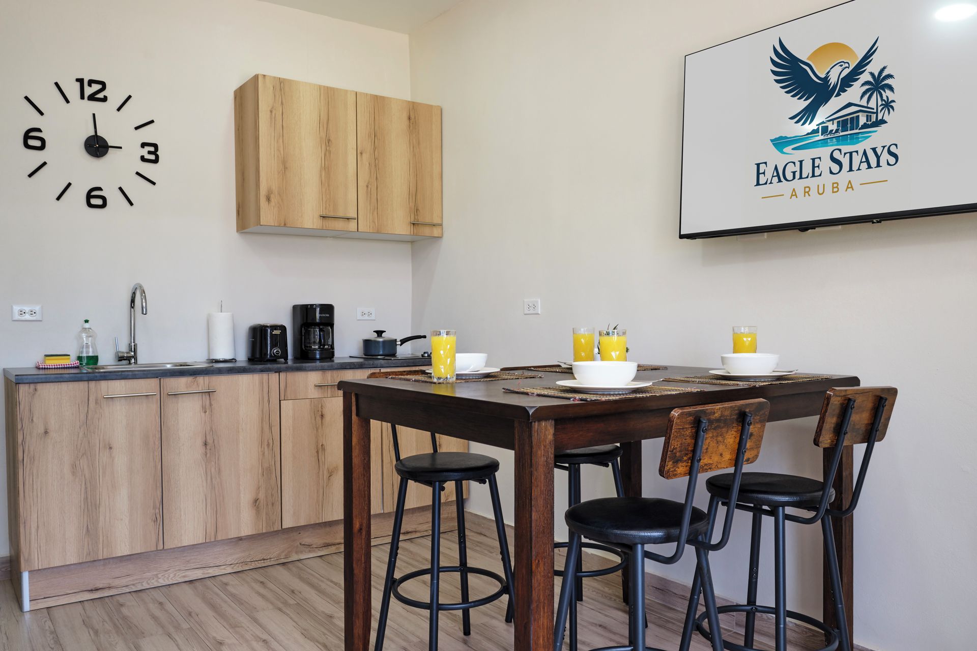 A modern kitchen with wooden cabinets, a coffee maker, and a clock on the wall.