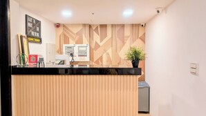 A reception desk with a wooden panel design, a security camera, and a QR code sign. - Yen Inn (New Taipei City)